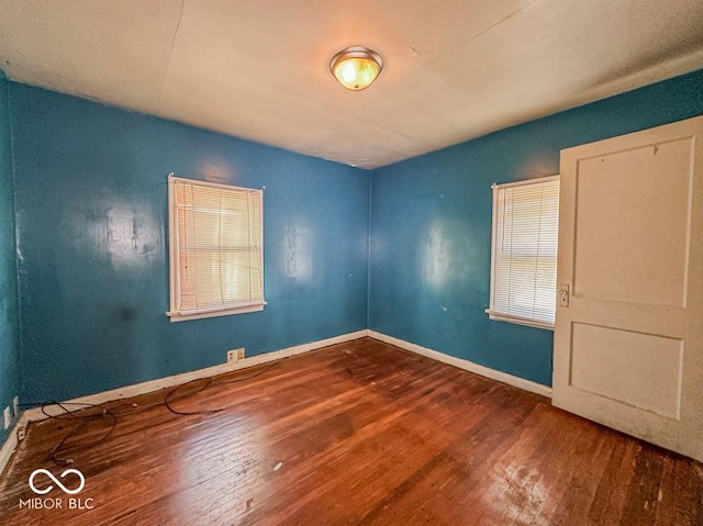 spare room featuring baseboards and wood finished floors