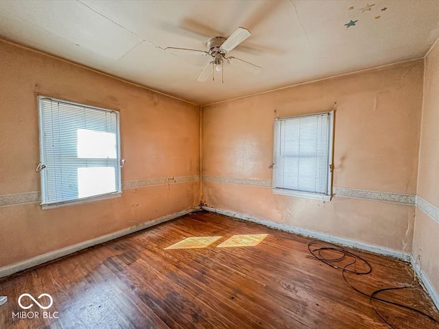 unfurnished room featuring hardwood / wood-style floors, a ceiling fan, and baseboards