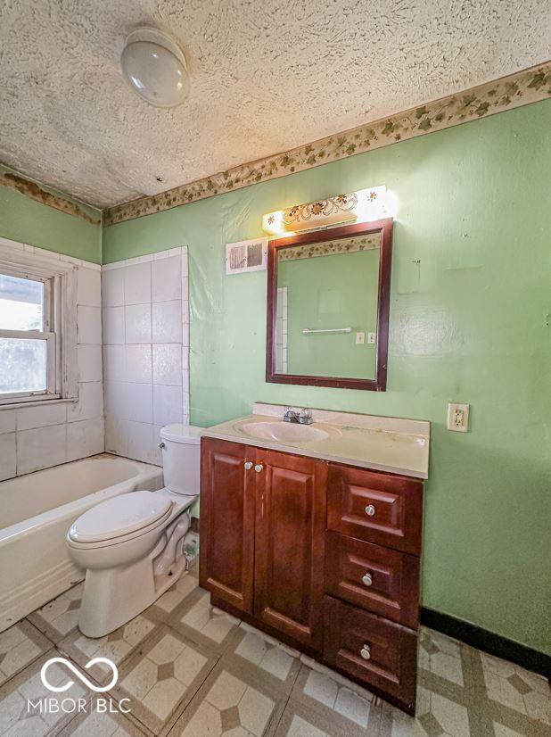 bathroom featuring tile patterned floors, a textured ceiling, vanity, and toilet