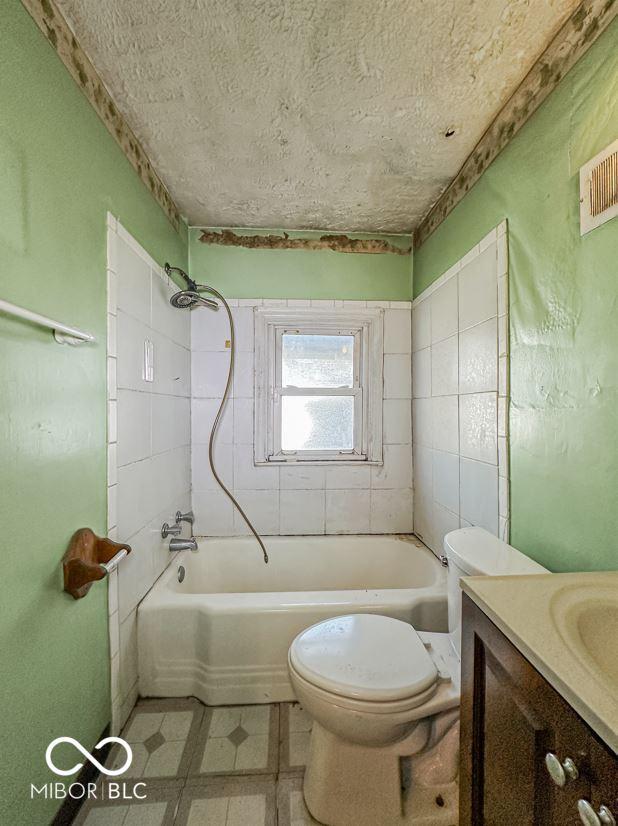 bathroom with tile patterned floors, toilet, a textured ceiling, bathing tub / shower combination, and vanity