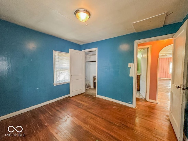 unfurnished bedroom featuring wood finished floors, baseboards, and a closet