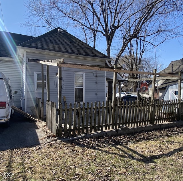 view of home's exterior featuring a fenced front yard and roof with shingles