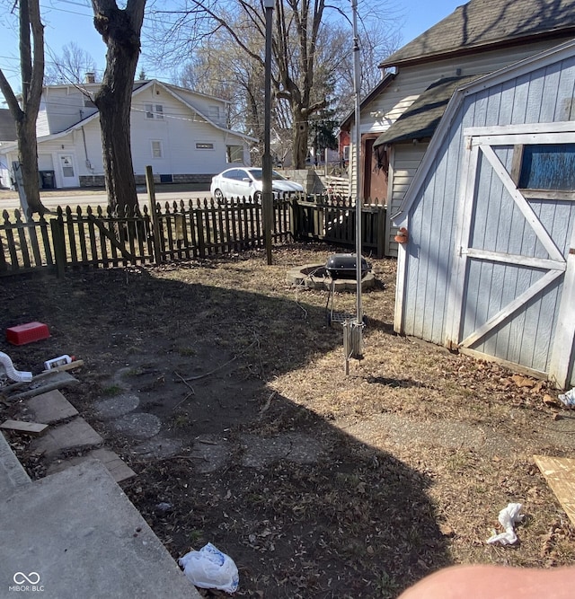 view of yard featuring an outbuilding, a storage unit, fence, and a residential view