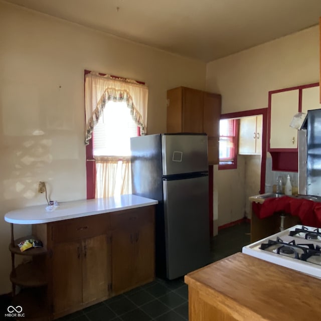 kitchen featuring open shelves, dark tile patterned flooring, light countertops, and freestanding refrigerator