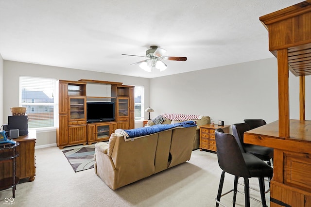 living room featuring light carpet, baseboards, and a ceiling fan