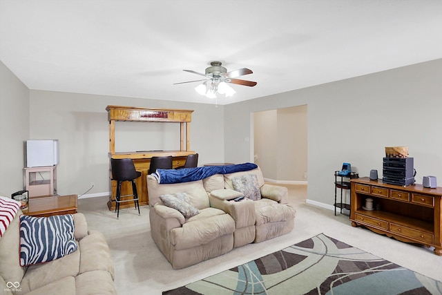 living area with light colored carpet, baseboards, and a ceiling fan