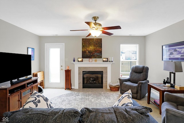 living area with light colored carpet, ceiling fan, and a tile fireplace