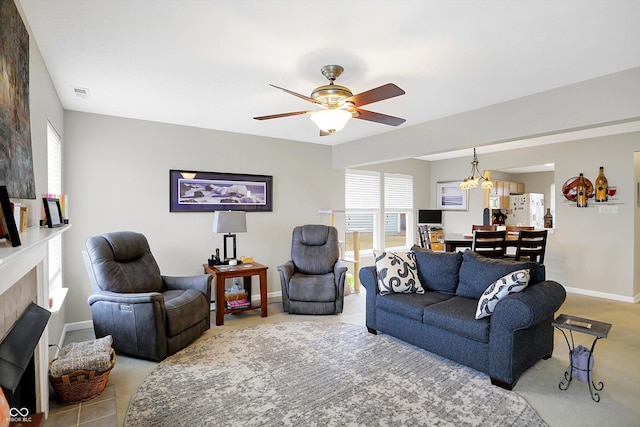 living room featuring visible vents, ceiling fan with notable chandelier, a fireplace, and baseboards