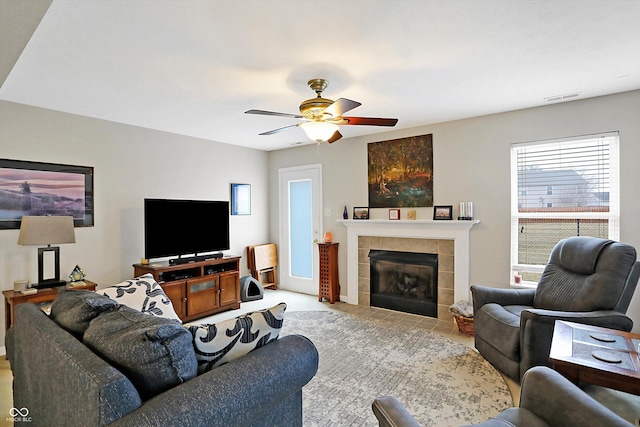 living room with visible vents, ceiling fan, and a tiled fireplace