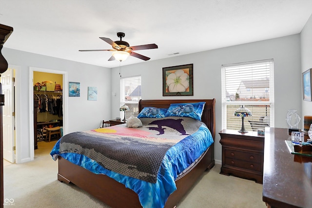 carpeted bedroom featuring a spacious closet, visible vents, a closet, and a ceiling fan