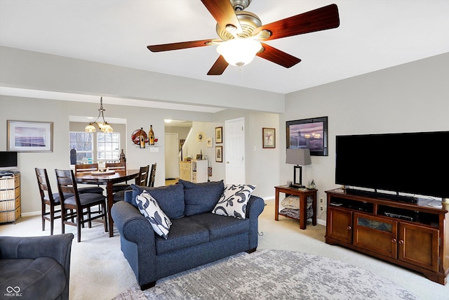 living room with baseboards, light colored carpet, and ceiling fan with notable chandelier