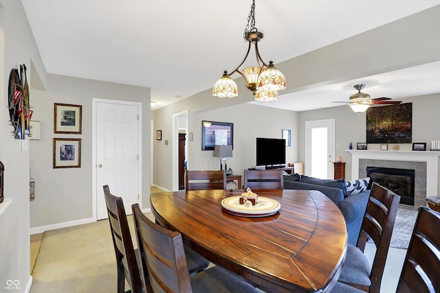 dining room featuring a tiled fireplace, a ceiling fan, and baseboards