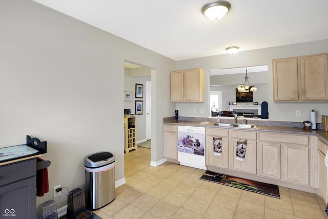 kitchen featuring baseboards, light brown cabinetry, dishwasher, a notable chandelier, and a sink