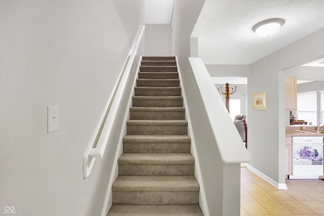 stairway with tile patterned flooring, baseboards, and a textured ceiling