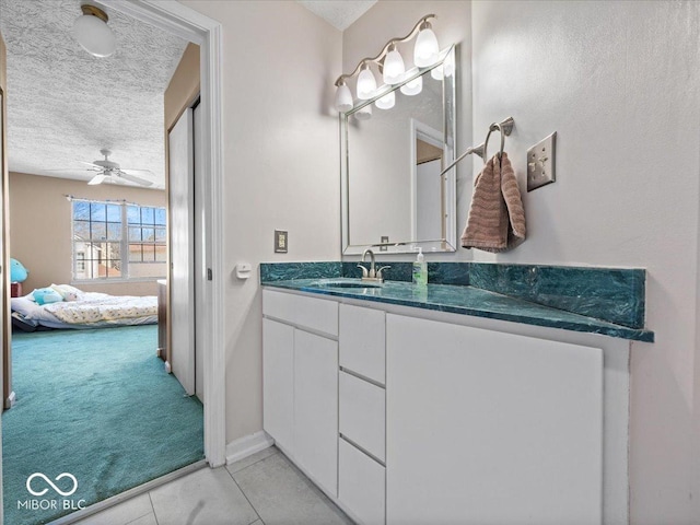 bathroom with a ceiling fan, a textured ceiling, ensuite bath, tile patterned flooring, and vanity