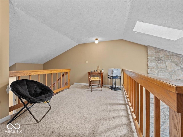 sitting room featuring baseboards, carpet, an upstairs landing, vaulted ceiling with skylight, and a textured ceiling