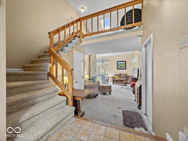 stairway featuring tile patterned floors, baseboards, carpet floors, and a towering ceiling