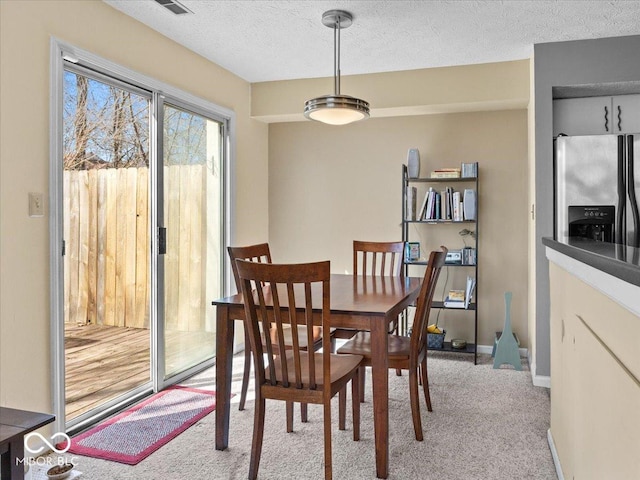 dining space featuring baseboards, light carpet, and a textured ceiling