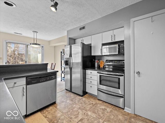 kitchen featuring visible vents, a textured ceiling, dark countertops, white cabinetry, and stainless steel appliances