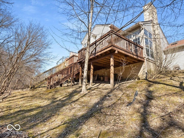 view of side of home with stairs, a chimney, and a wooden deck