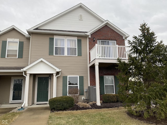 view of property with brick siding and a balcony