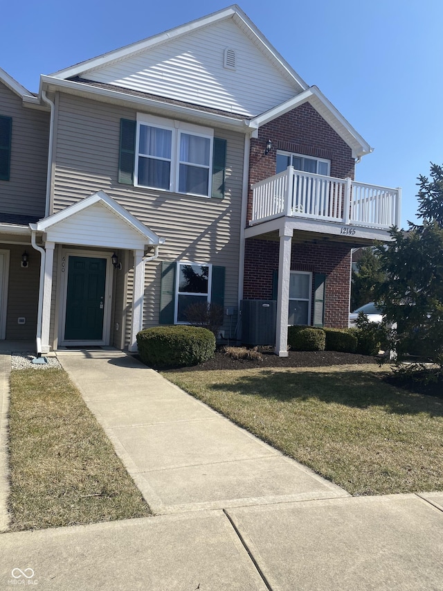 view of front of home featuring a front lawn, central AC unit, and brick siding