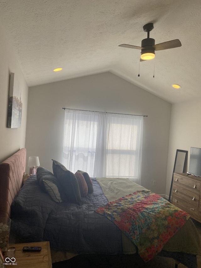 bedroom with a textured ceiling, ceiling fan, and vaulted ceiling