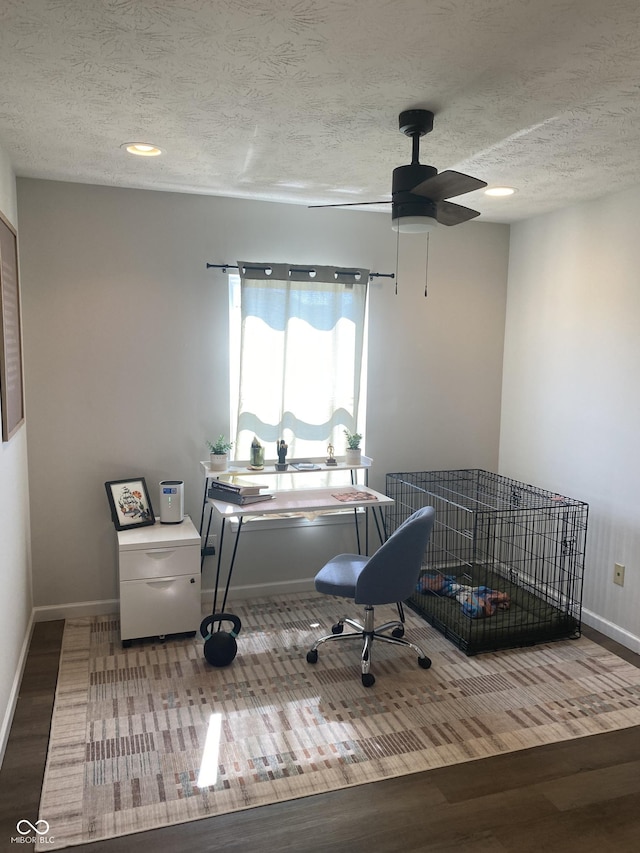 home office with ceiling fan, a textured ceiling, baseboards, and wood finished floors