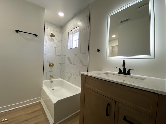 bathroom with visible vents, baseboards, shower / bath combination, wood finished floors, and vanity