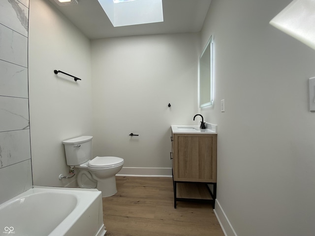 bathroom with toilet, wood finished floors, a skylight, baseboards, and a bathtub