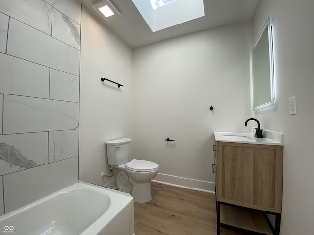 bathroom featuring toilet, a bathing tub, a skylight, wood finished floors, and vanity