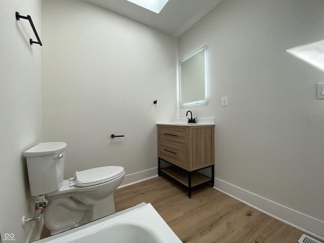 bathroom featuring visible vents, toilet, wood finished floors, a skylight, and baseboards