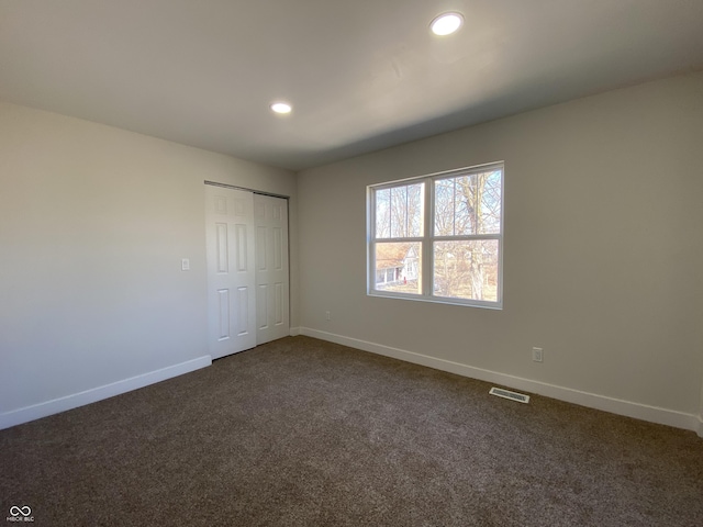 unfurnished bedroom with visible vents, baseboards, recessed lighting, a closet, and dark colored carpet