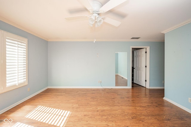 spare room featuring a ceiling fan, crown molding, wood finished floors, and baseboards