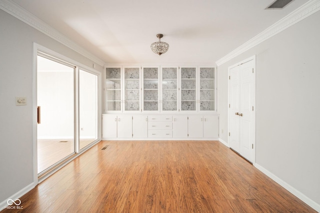 empty room featuring visible vents, crown molding, and light wood-style floors