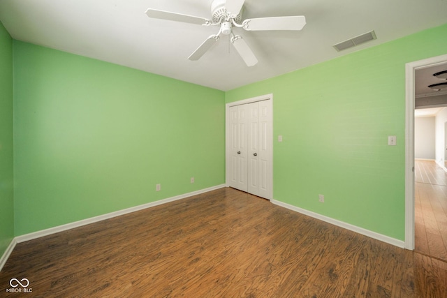 unfurnished bedroom featuring a closet, visible vents, baseboards, and wood finished floors