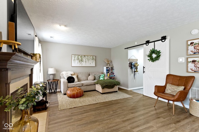 12612 Clearview Ln, Indianapolis, IN 46236 - living area featuring a barn door, a textured ceiling, light wood-type flooring, a tiled fireplace, and baseboards