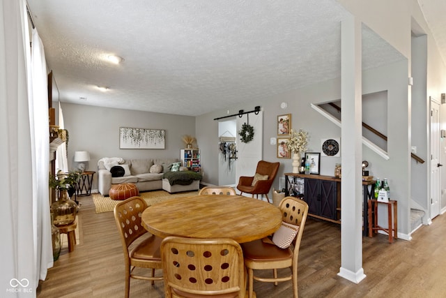 12612 Clearview Ln, Indianapolis, IN 46236 - dining room with stairs, light wood finished floors, a textured ceiling, and baseboards