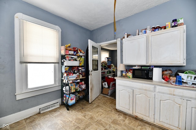 kitchen featuring light countertops, white cabinets, visible vents, and black microwave