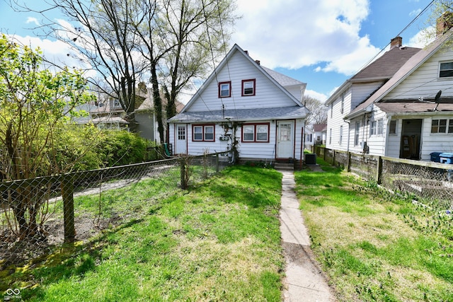 view of front of house featuring a shingled roof, fence private yard, a front yard, and entry steps