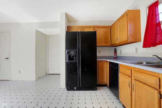 kitchen with light floors, light countertops, brown cabinets, black appliances, and a sink