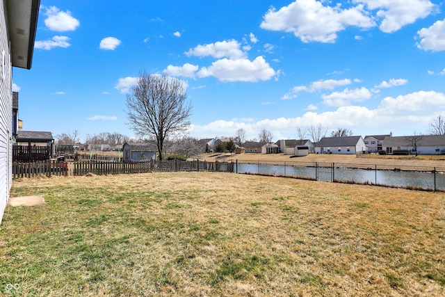 view of yard featuring a residential view, a water view, and fence