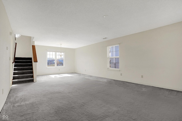 interior space with stairway, a textured ceiling, and carpet floors