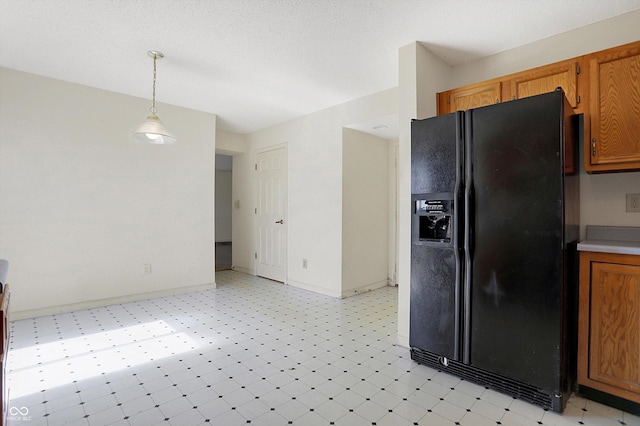 kitchen featuring pendant lighting, light floors, baseboards, and black refrigerator with ice dispenser