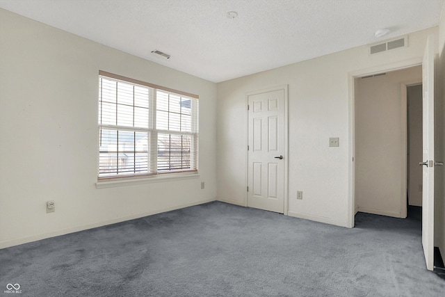 unfurnished bedroom with visible vents, carpet floors, a textured ceiling, and baseboards