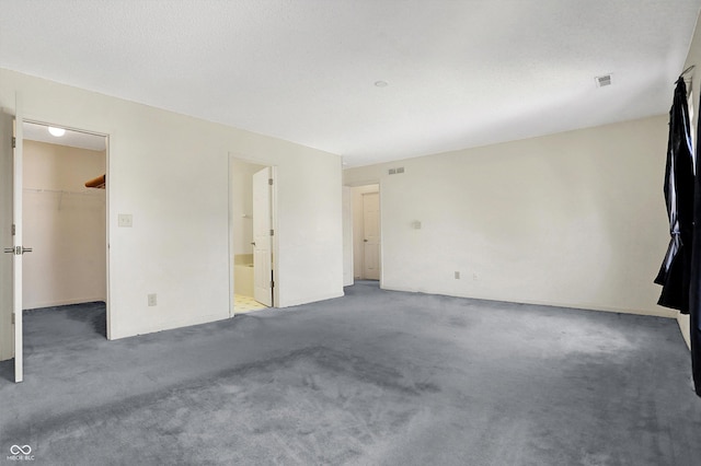 unfurnished bedroom with a walk in closet, visible vents, and carpet flooring