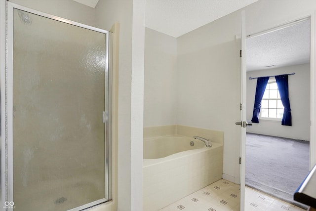 full bathroom featuring a garden tub, a textured ceiling, and a shower stall