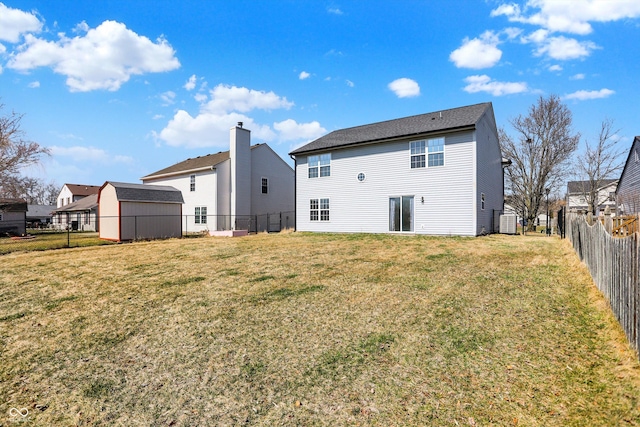 back of property featuring an outdoor structure, a shed, a lawn, and a fenced backyard