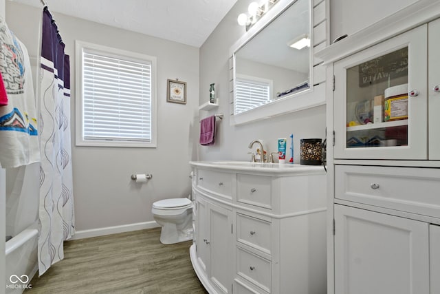 full bath with shower / bath combo with shower curtain, vanity, wood finished floors, toilet, and baseboards