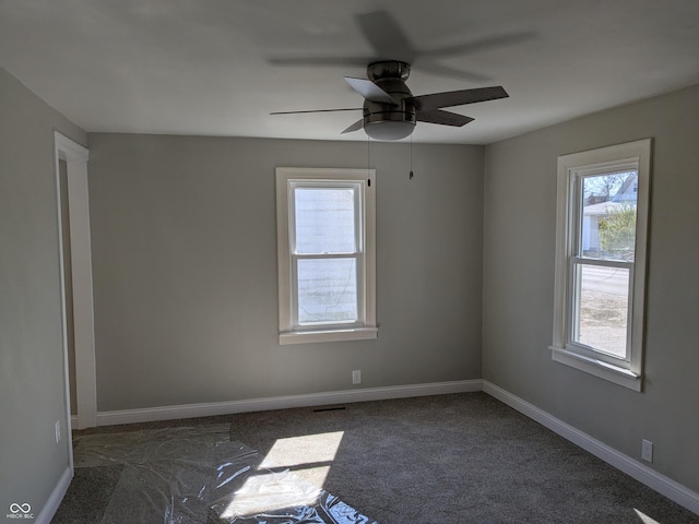 carpeted empty room with visible vents, ceiling fan, and baseboards